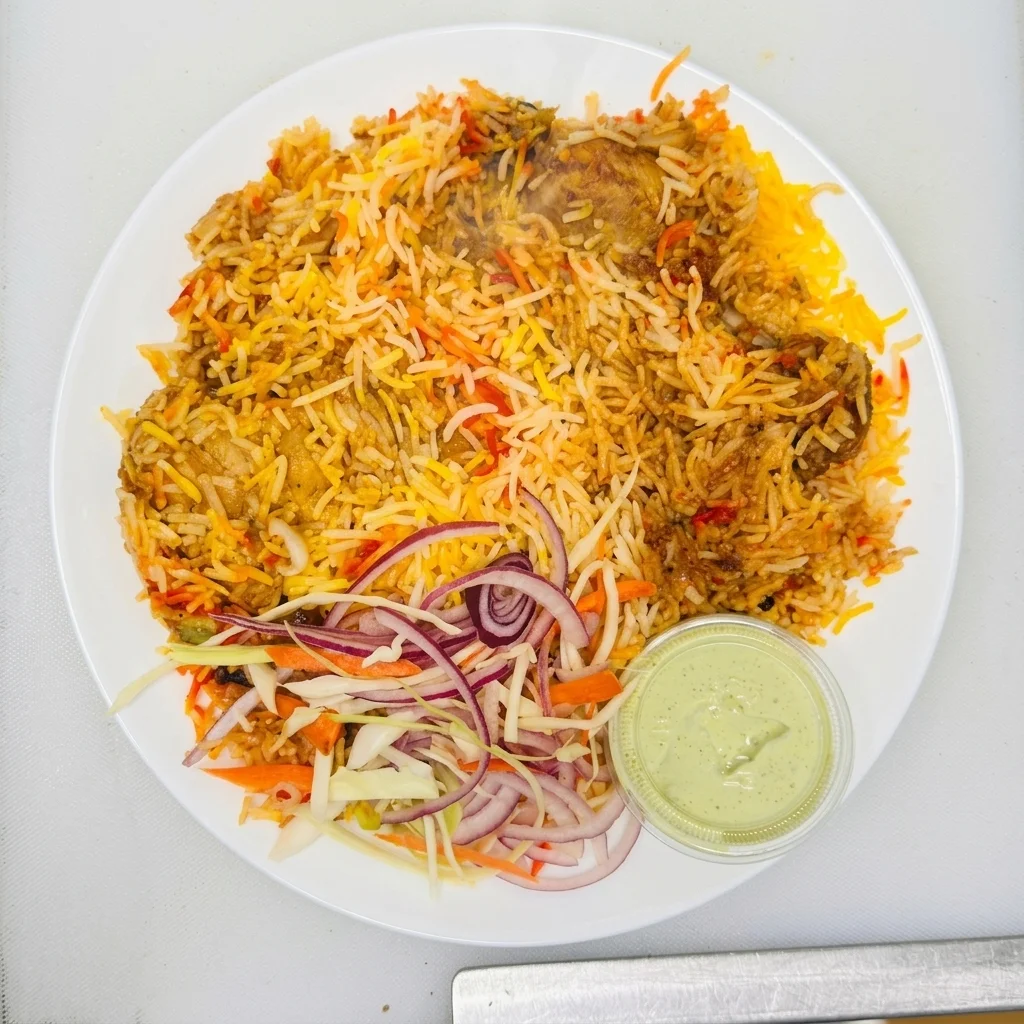 Chicken Biryani — fragrant basmati rice layered with spiced chicken, served with raita at Chenab Pakistani Restaurant Edmonton